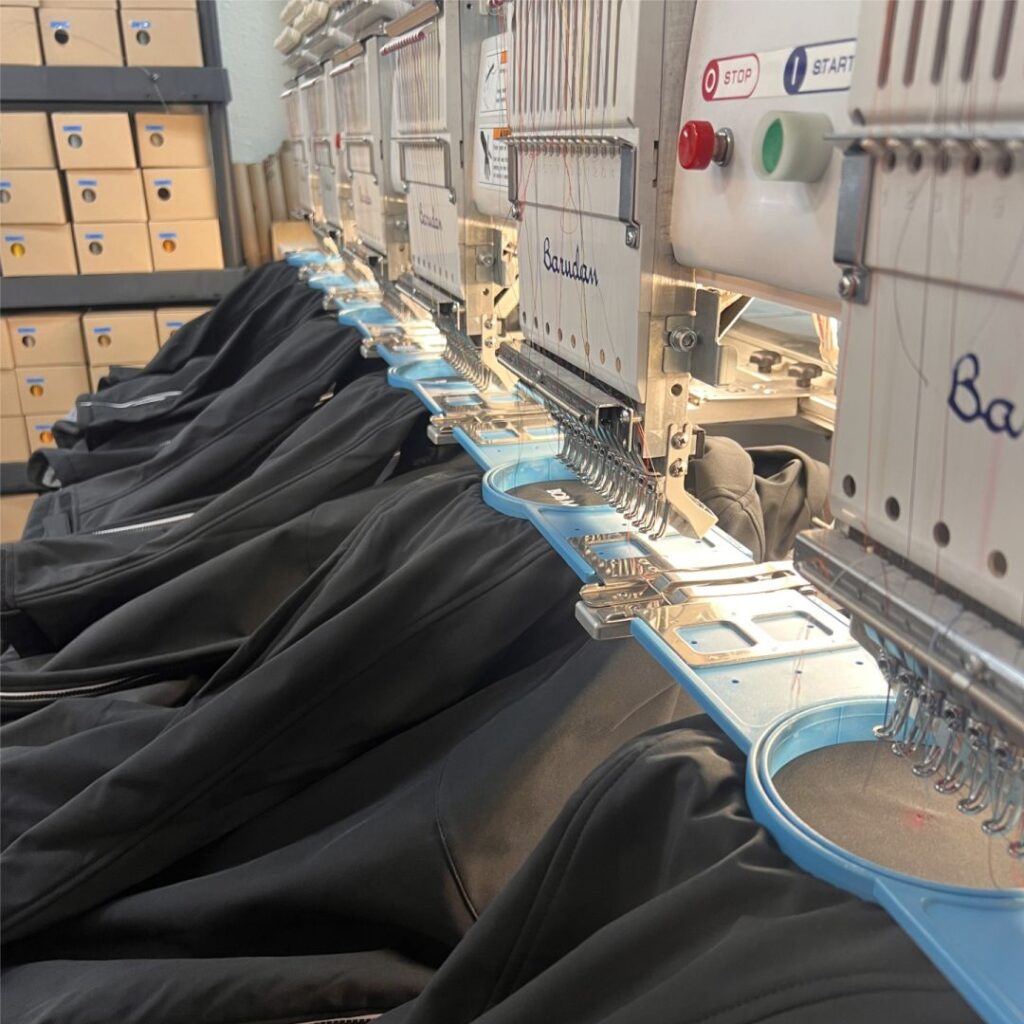 Embroidery machines working on black garments.