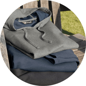 Stack of hoodies on a wooden bench.